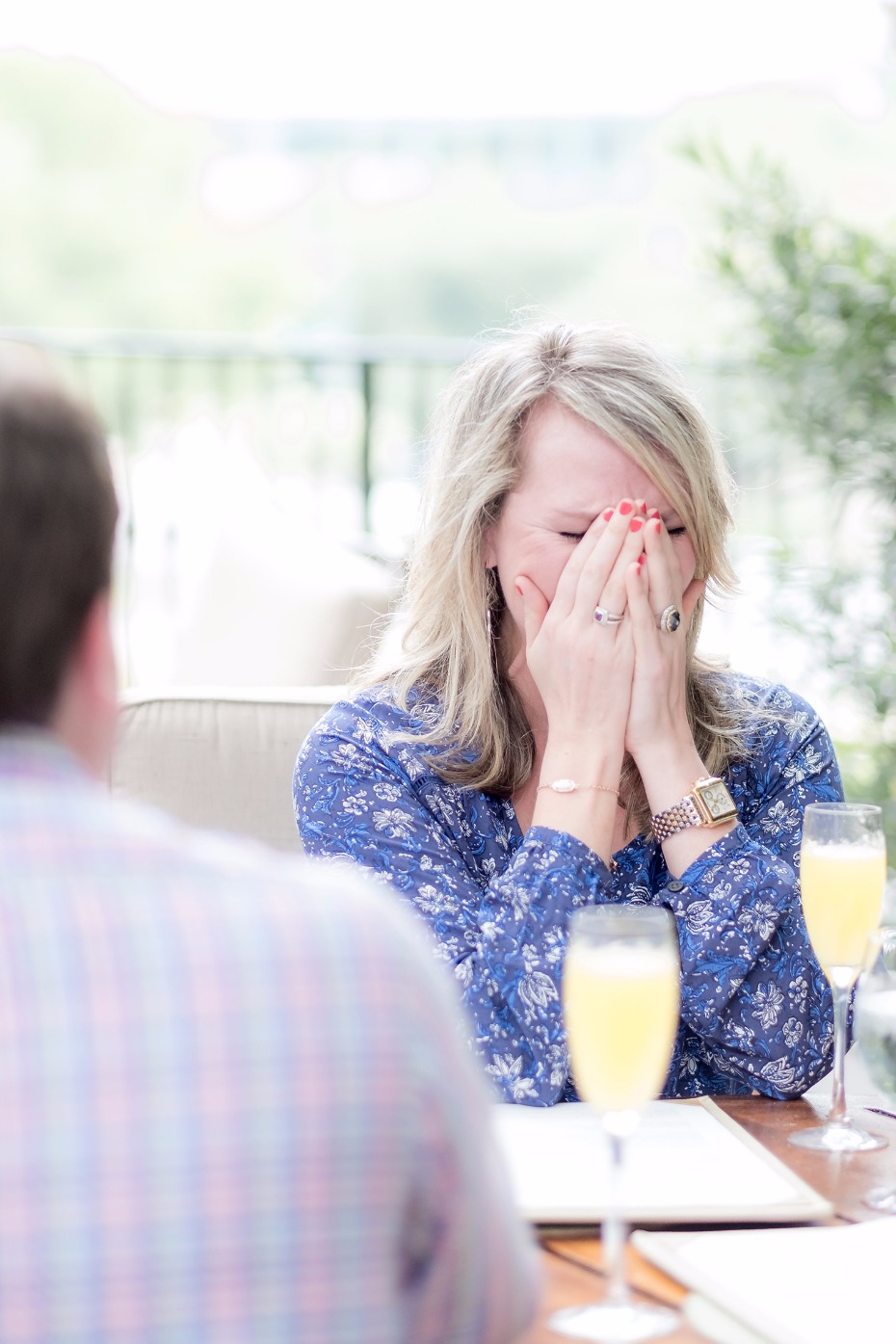 Woman laughing, covering face with hands at brunch