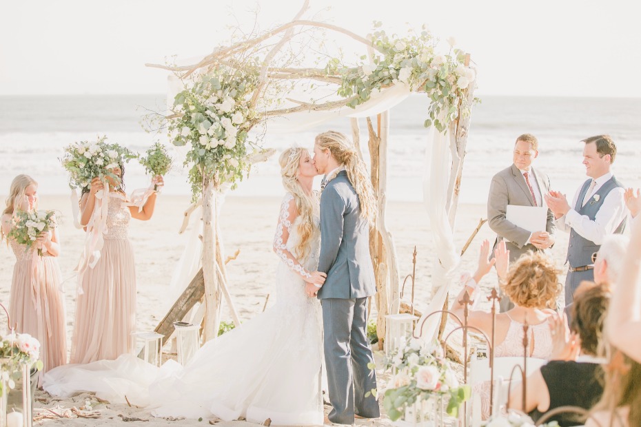 a wedding kiss on a sun soaked California beach