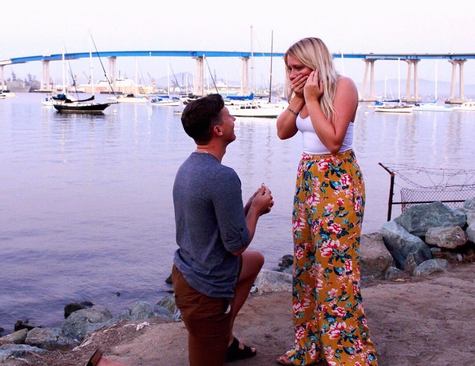 A man proposes to a woman at a waterfront location