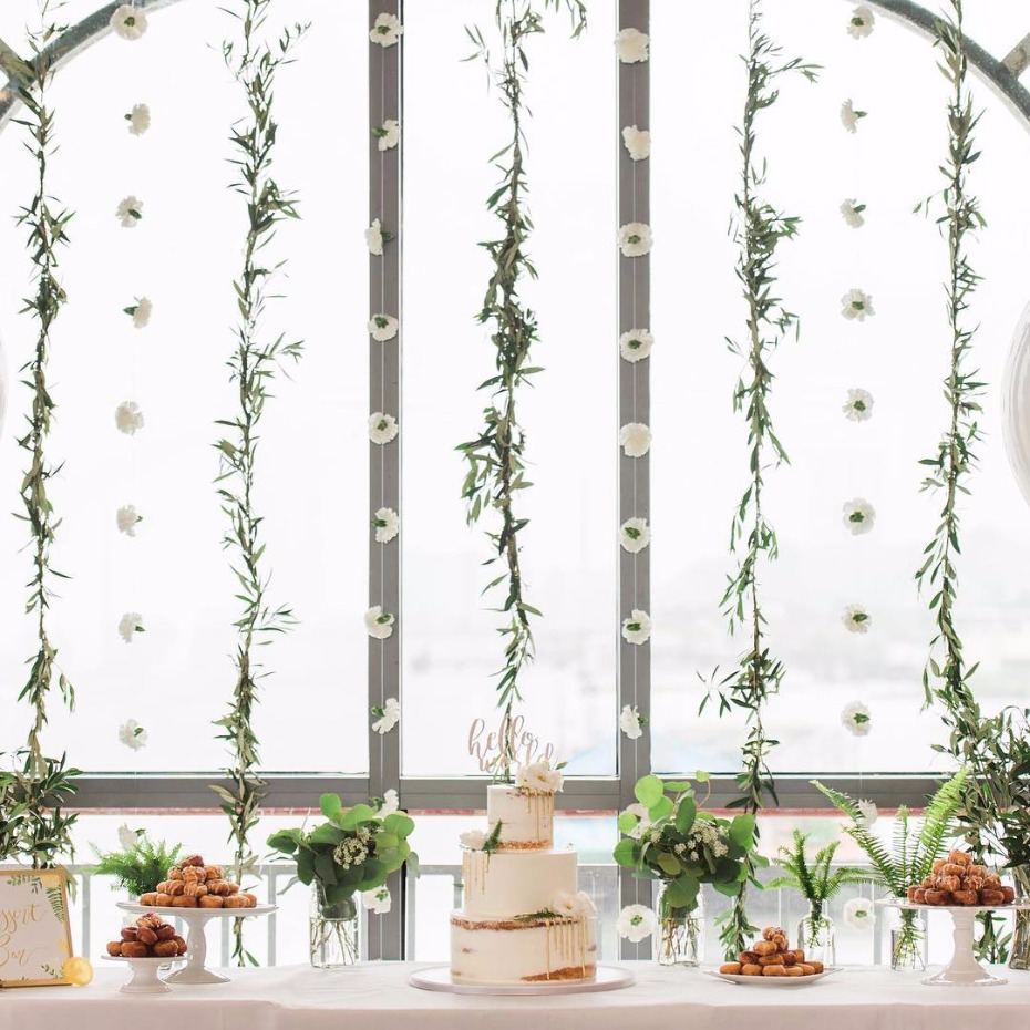 Elegant wedding cake and floral decor against window backdrop