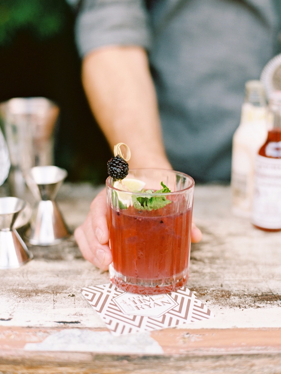 Hand holding blackberry cocktail with lime and mint