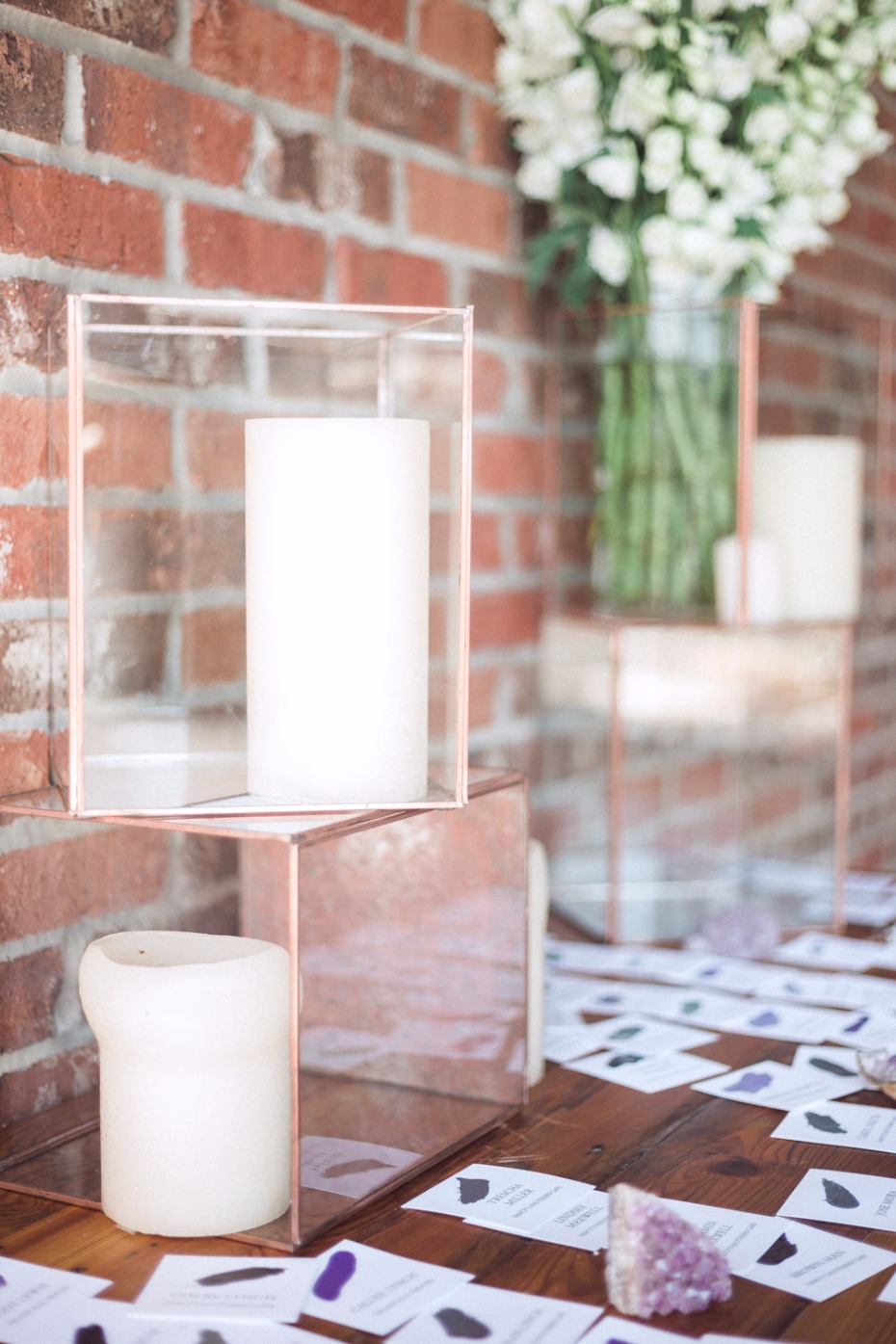 White candles and floral decor on a table with brick background