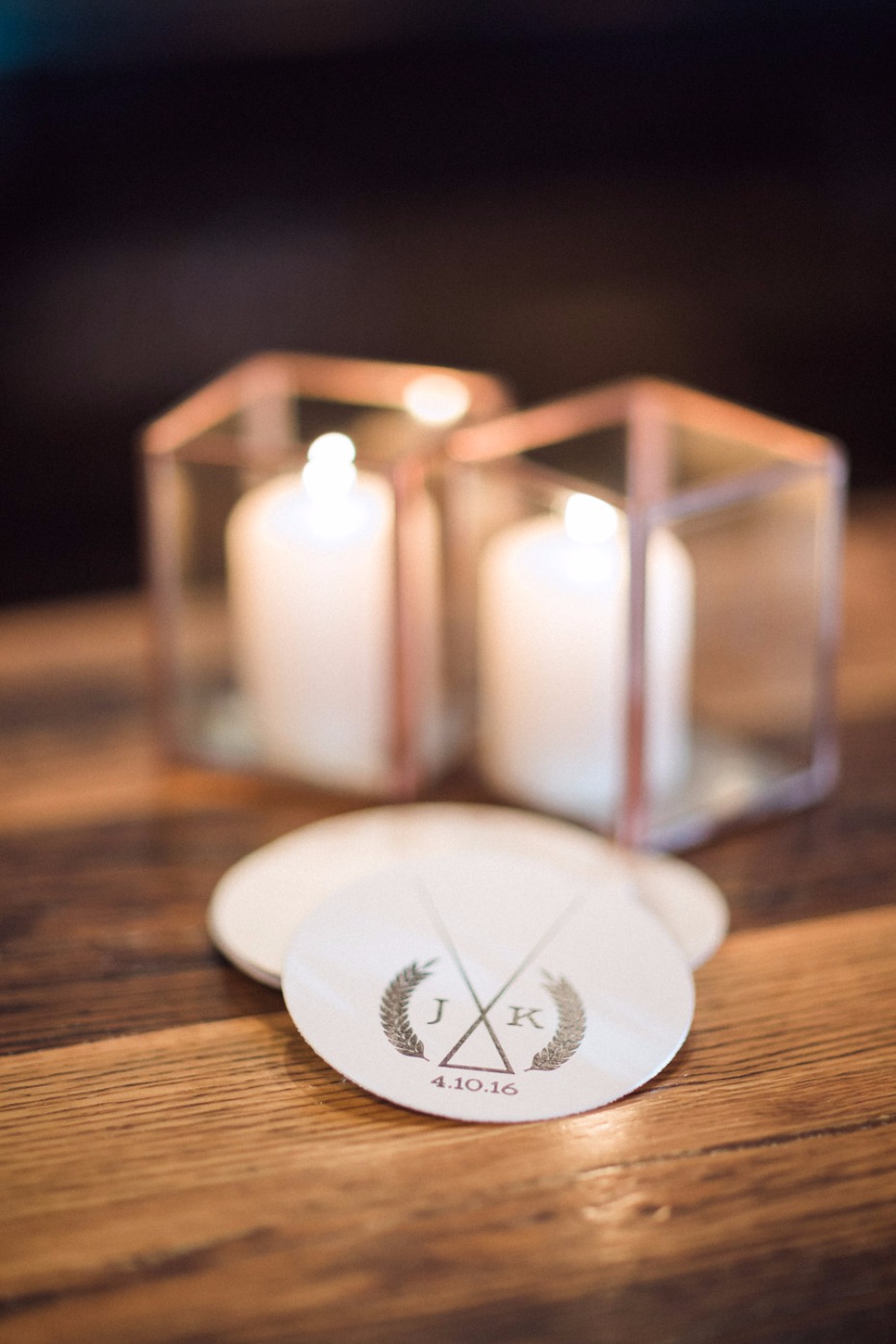 Wedding decor with candles and custom coasters on wooden table