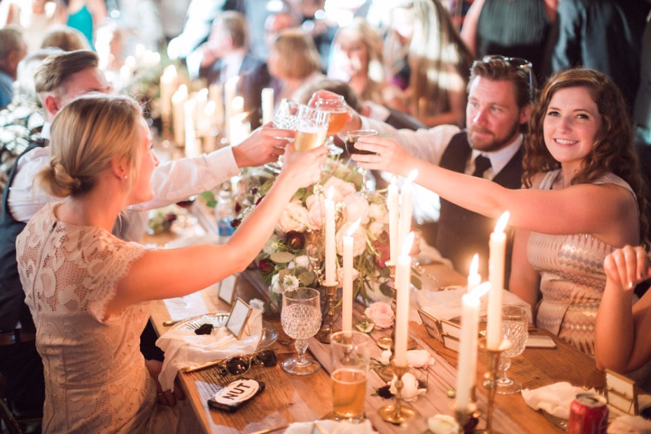 Guests toasting drinks at a candlelit wedding reception