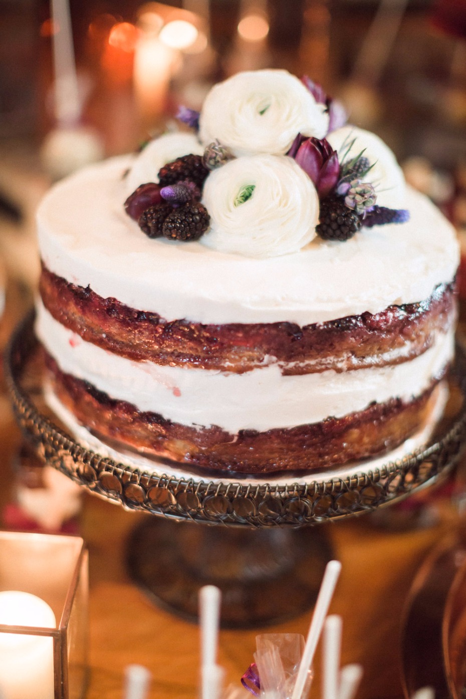 Elegant cake with white flowers and berries on a silver cake stand