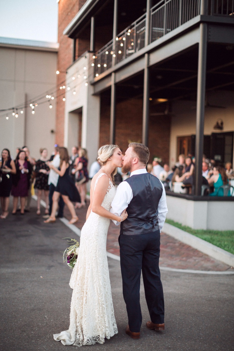 Bride and groom share a romantic kiss at outdoor wedding reception