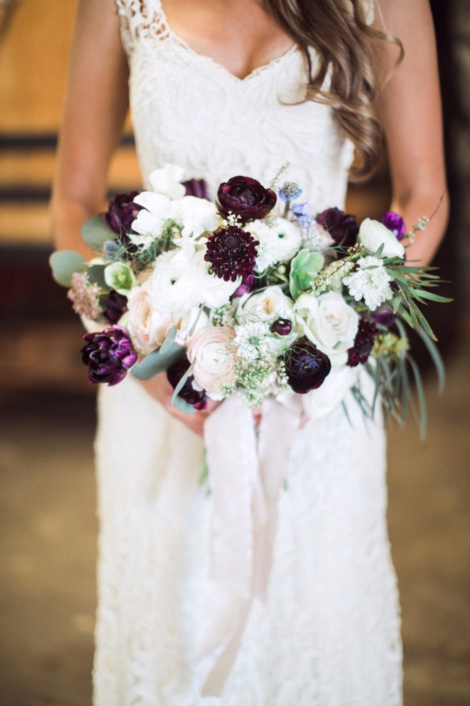 Bride in white lace dress holding elegant floral bouquet