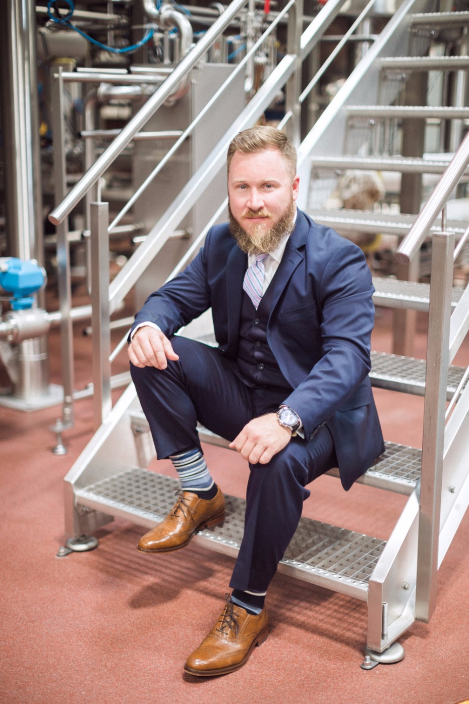 Businessman sits on factory stairs, confident pose