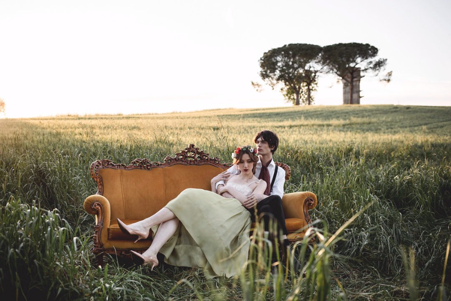 Couple sitting on couch in field romantic portrait at sunset