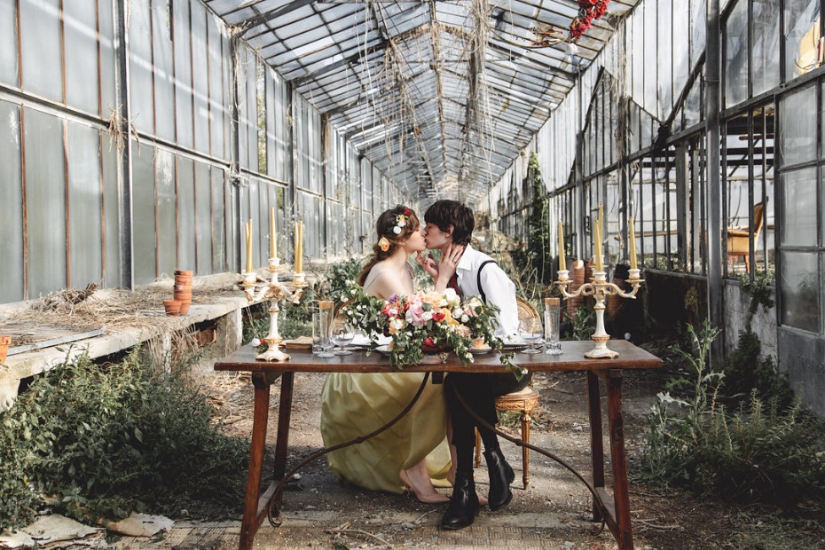 Couple kissing at greenhouse wedding reception table