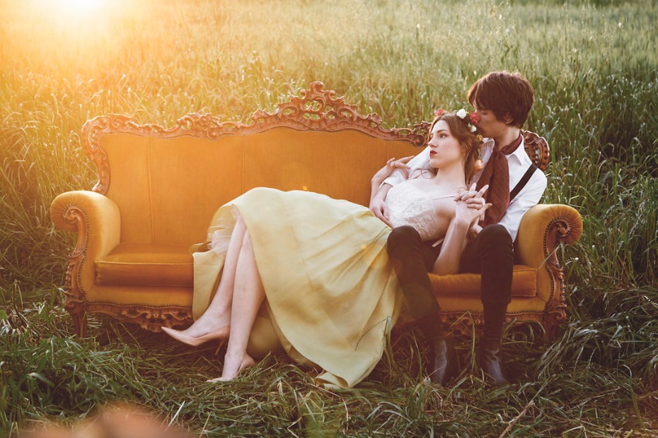 Couple on an antique sofa in a sunlit field of tall grass
