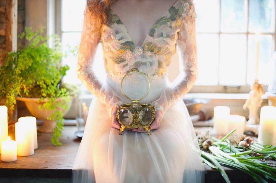 Bride holds a golden heirloom box near candles