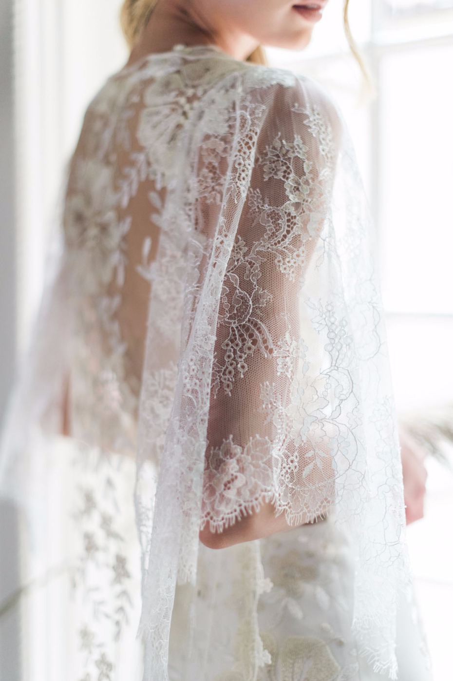 Bride in delicate white lace wedding shawl back view