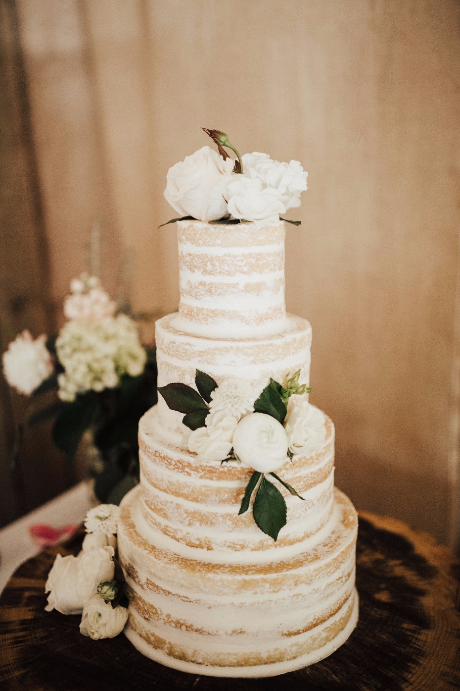 Naked wedding cake with flowers and powdered sugar