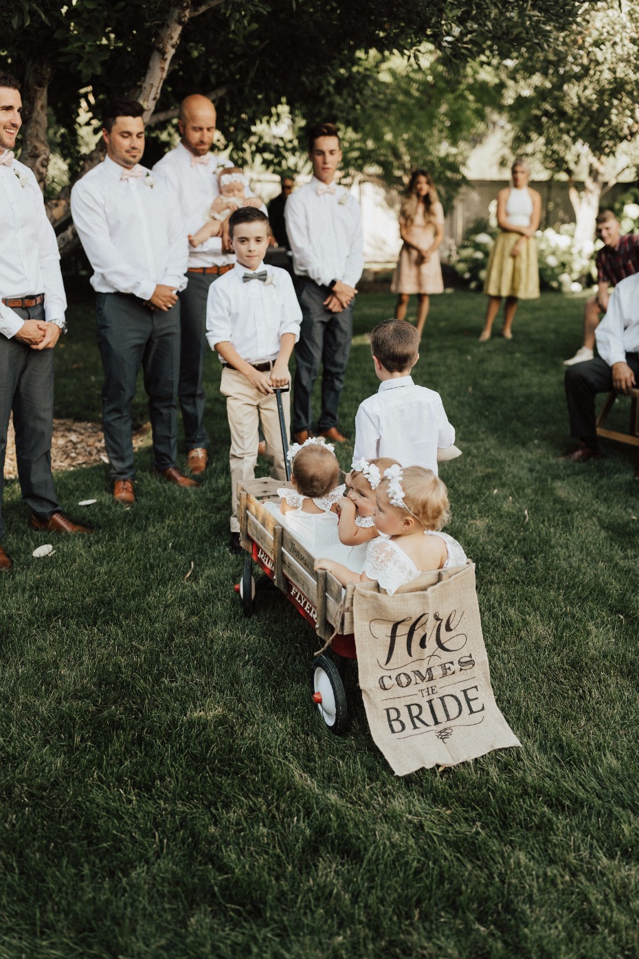 flower babies in a wagon with burlap sign of here comes the bride