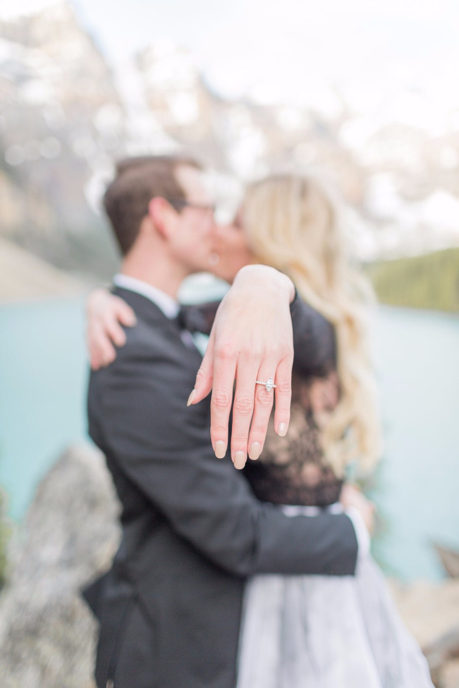 Newly engaged couple kissing with engagement ring shown