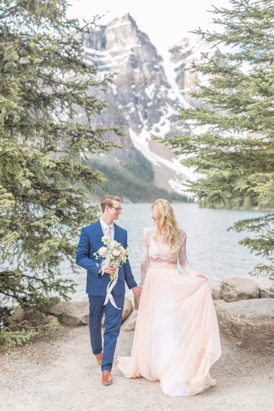 Bride and groom walking hand in hand near a beautiful lake