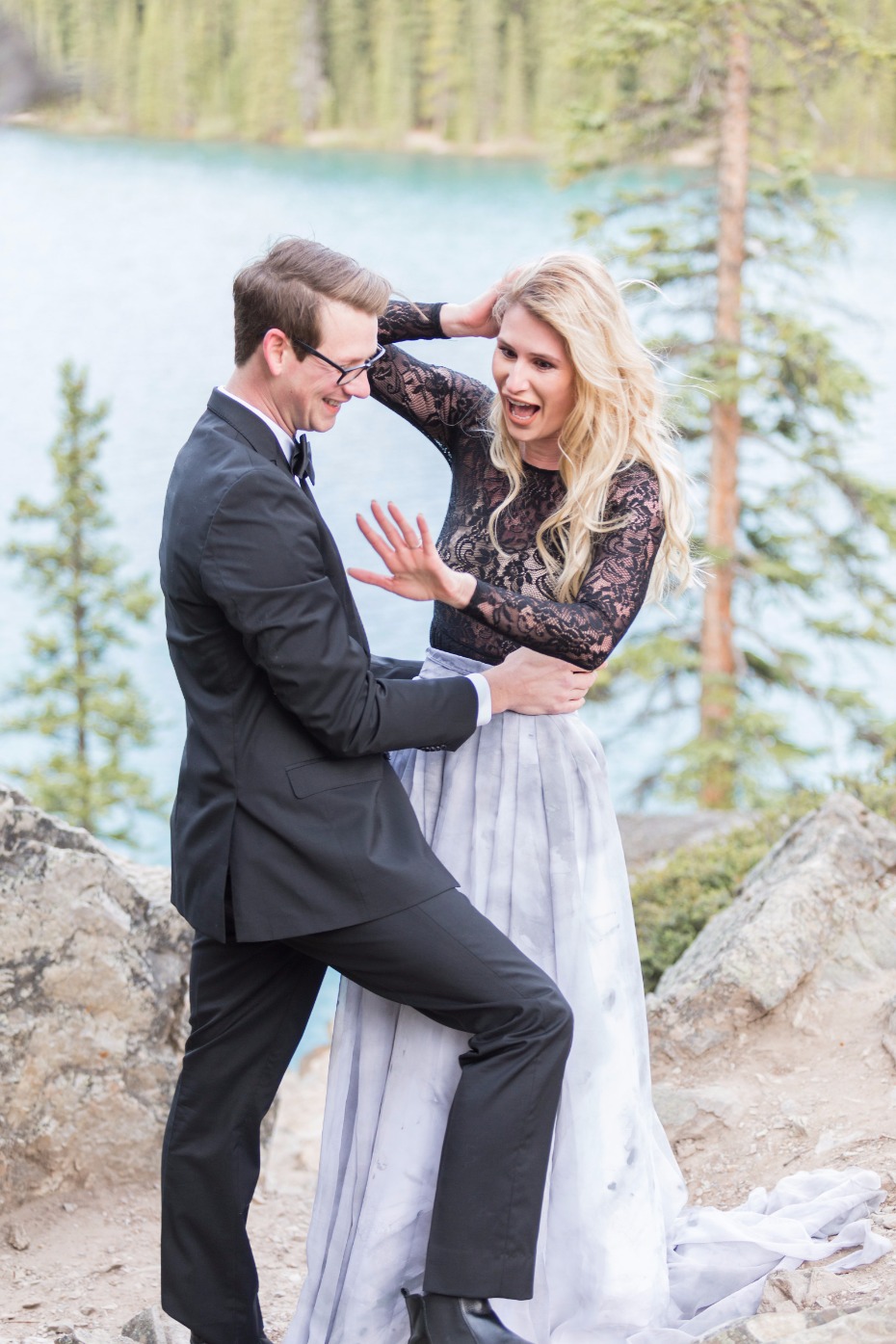 Funny engaged couple posing outdoors by a mountain lake