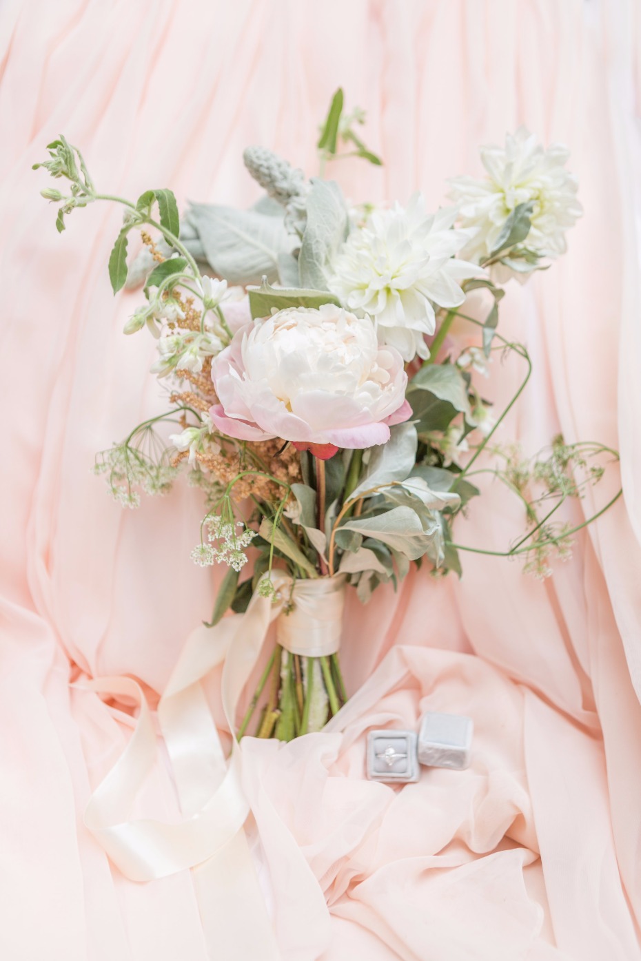 Elegant bridal bouquet with engagement ring on a soft pink background