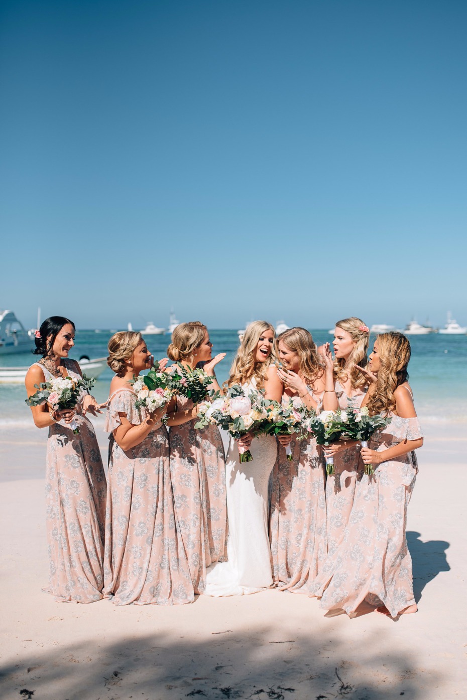 bridesmaids in long pink floral dresses on the beach in Mexico