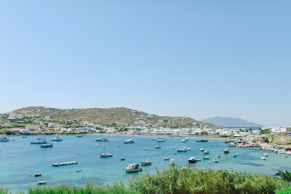 Boats in a bay with a town on a hill under a blue sky