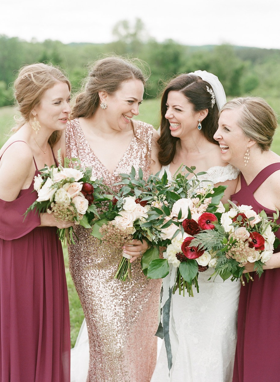 Bride and bridesmaids laugh holding wedding bouquets