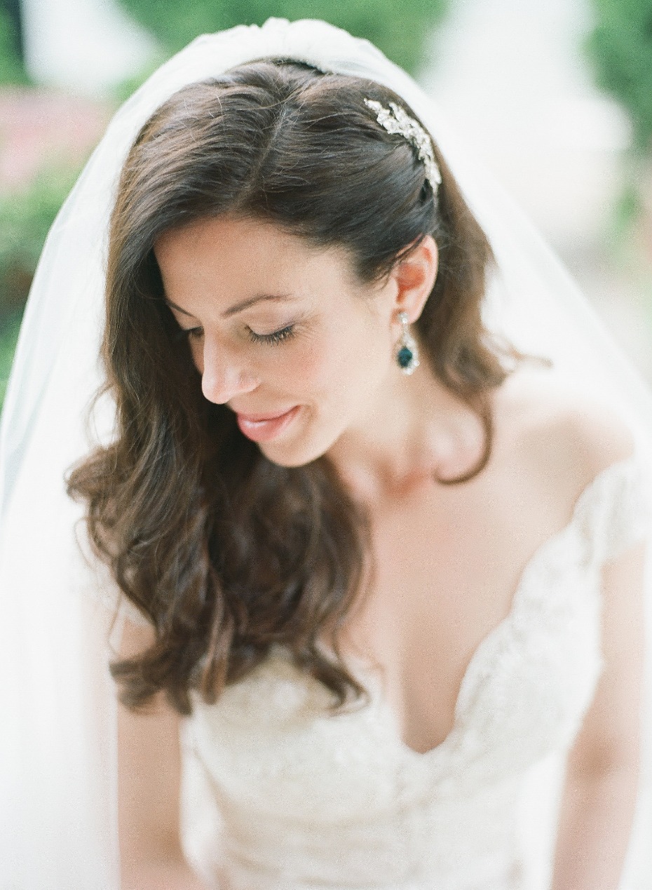 Bride with veil earring and hairpiece smiles softly
