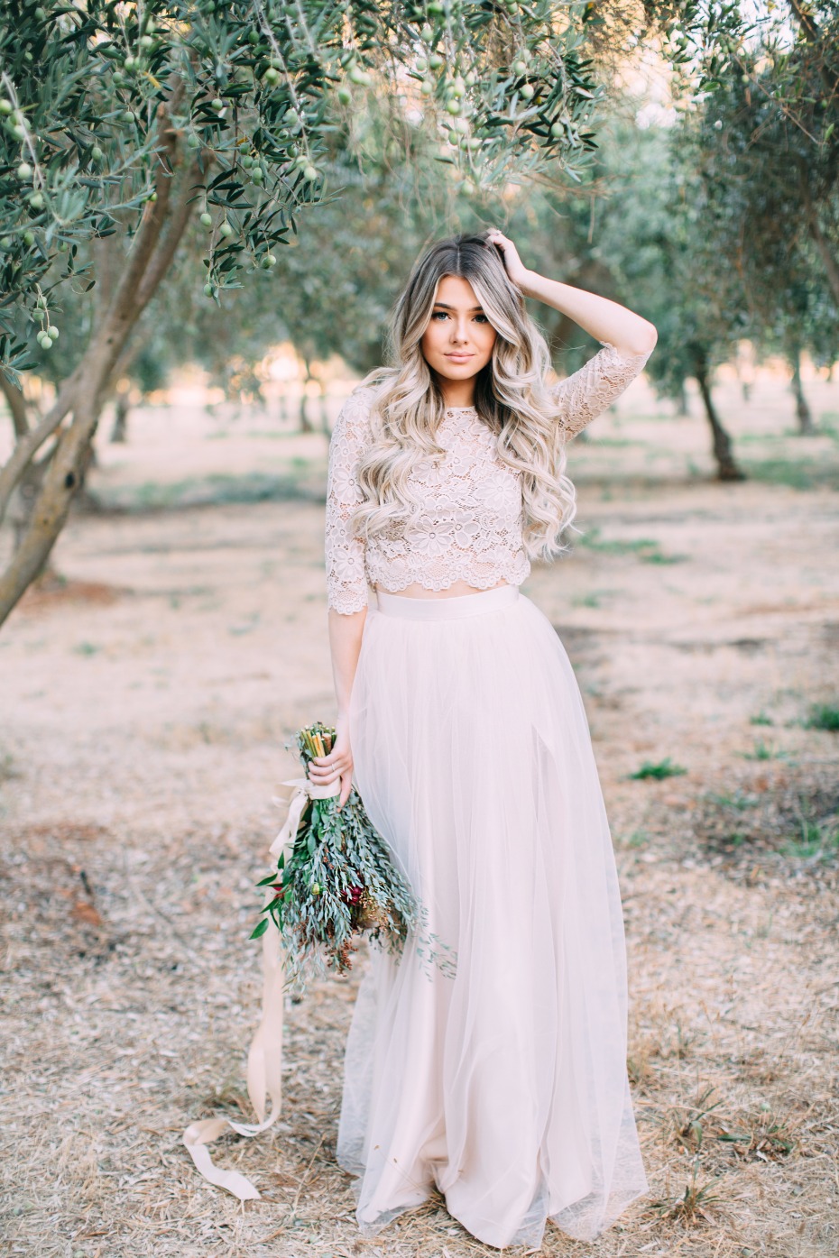 Beautiful bride in lace top and tulle skirt holds bouquet