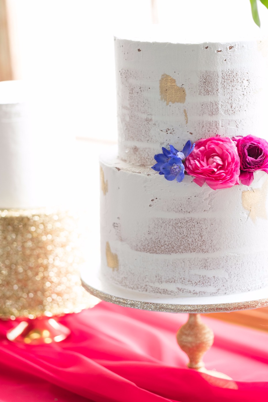 nearly naked wedding cake accented with jewel tone flowers