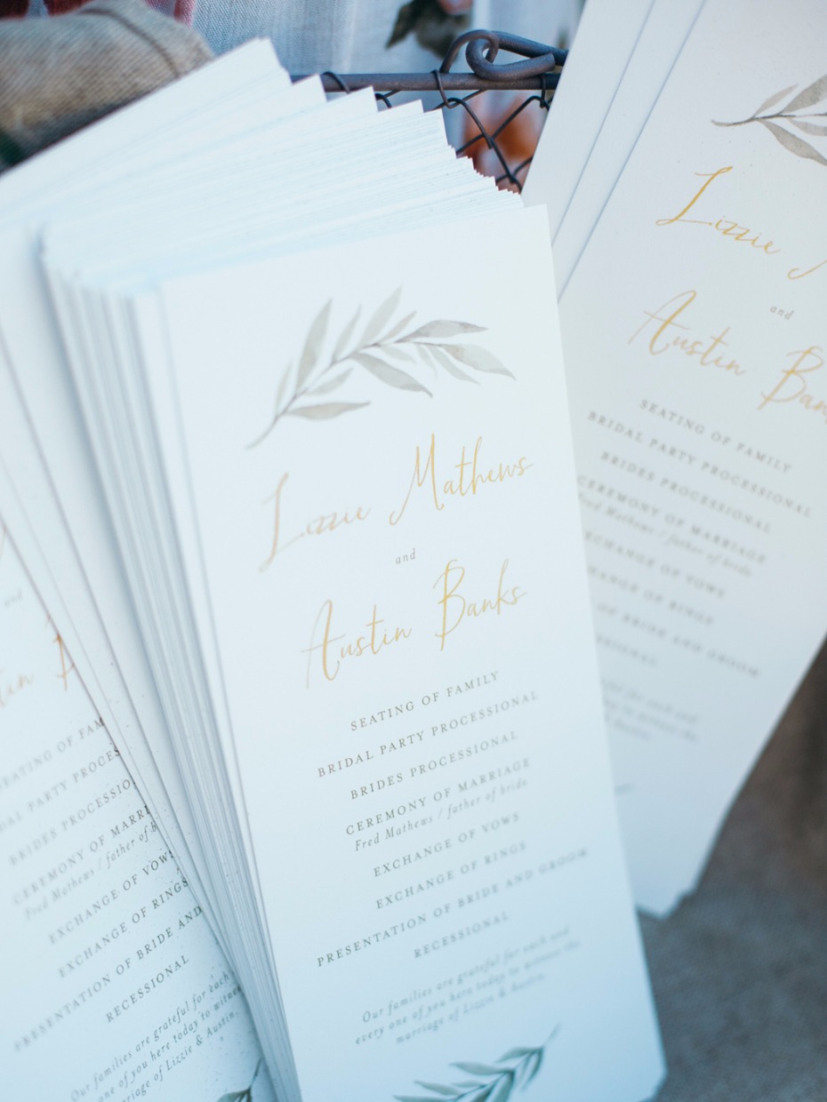 wedding programs with elegant greenery and gold calligraphy