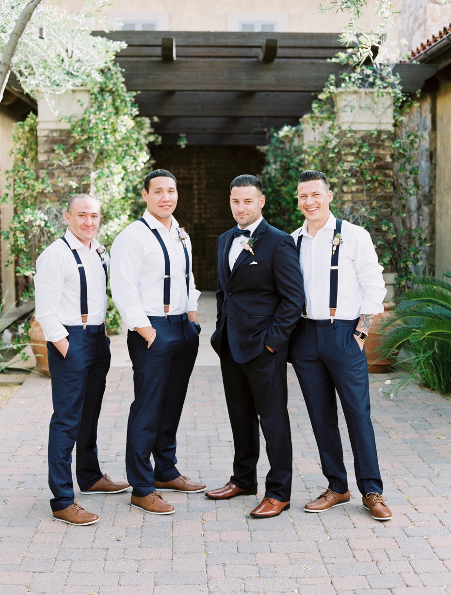 groom in navy suit and groomsmen in suspenders and navy slacks
