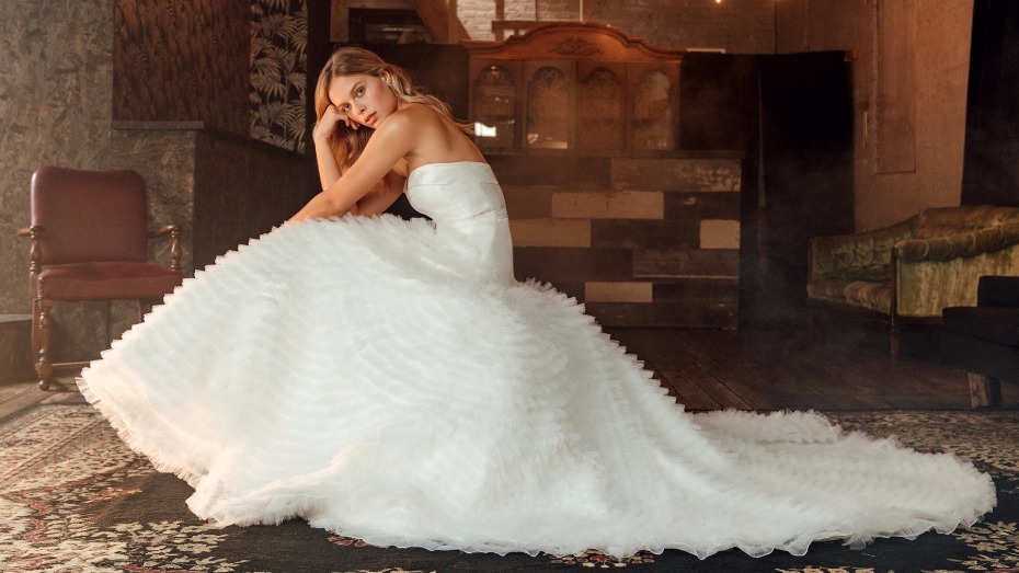 Woman in ruffled strapless wedding gown posing indoors