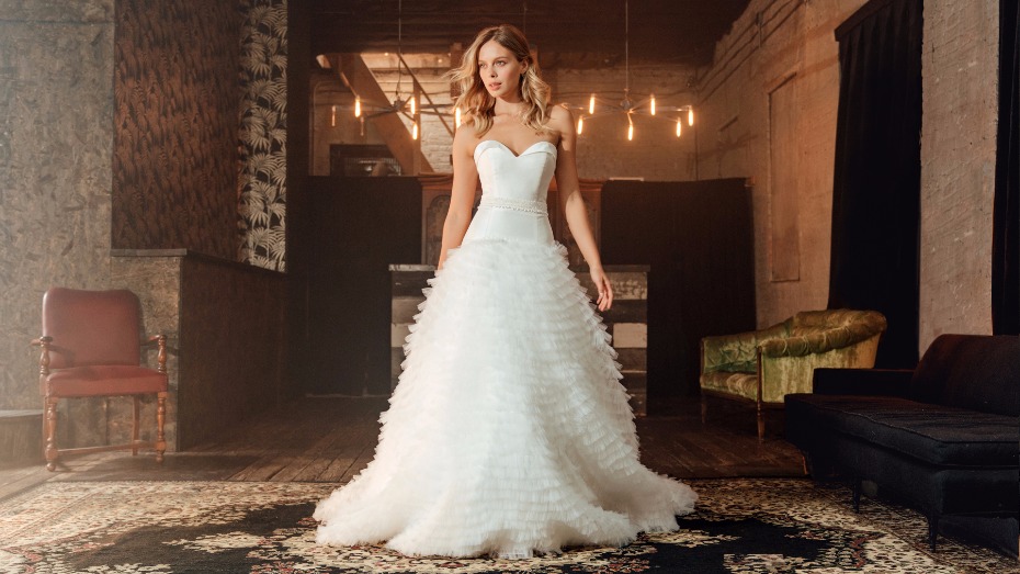 Bride in ruffled white gown in atmospheric loft space