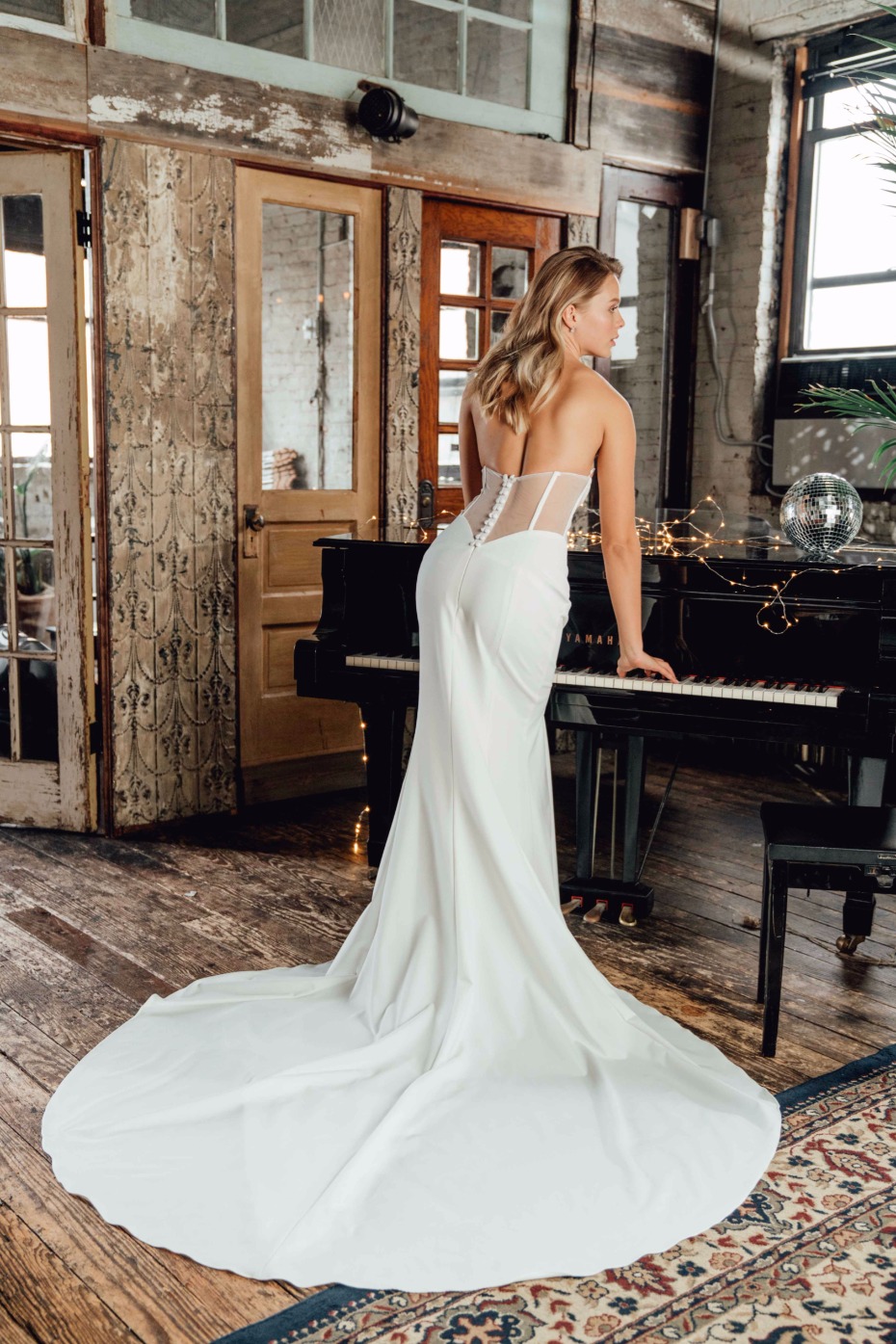Woman in white wedding dress at piano back view