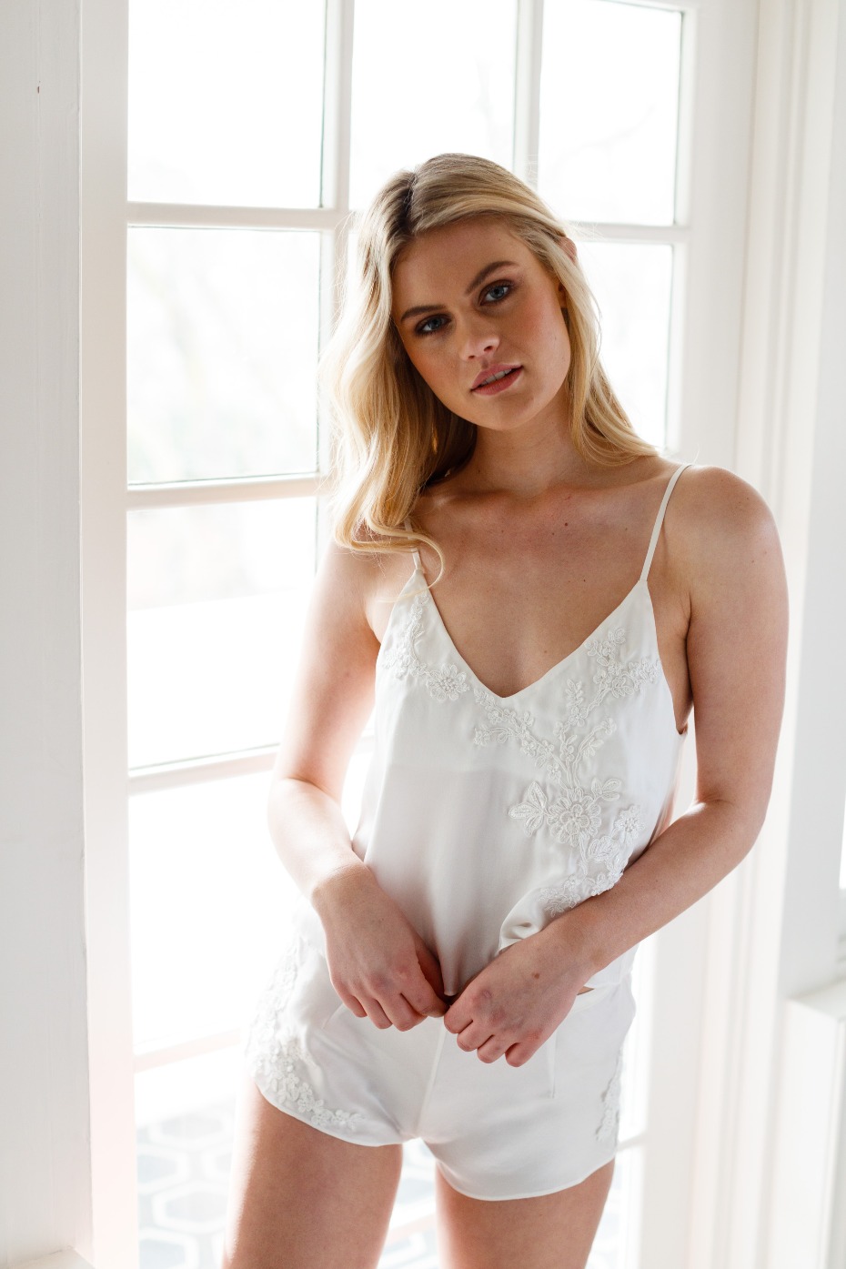 Blonde model in white lace lingerie set by window light