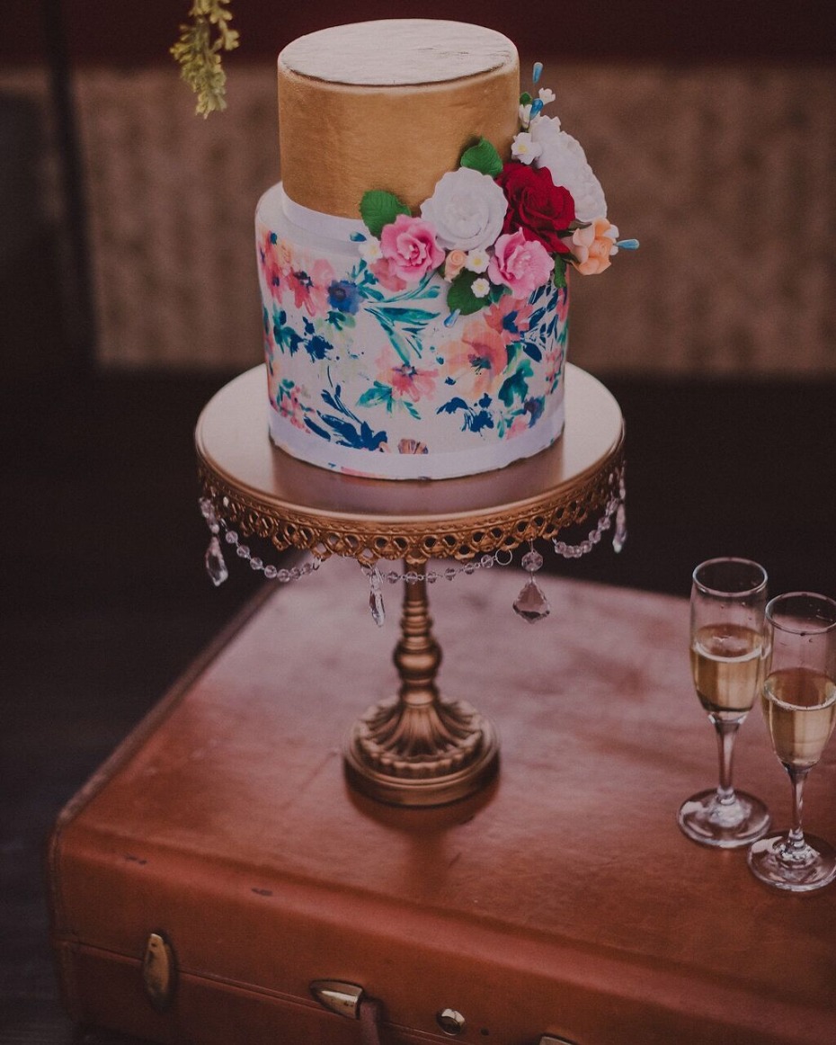 Elegant watercolor floral wedding cake on suitcase table
