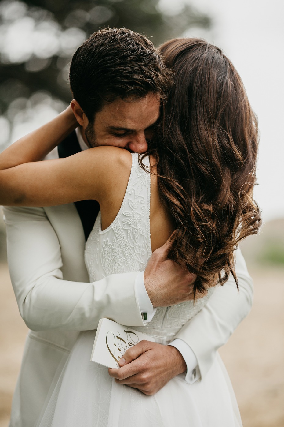 emotional groom hugs a supportive bride