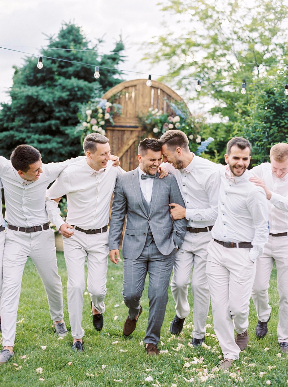 groom in light grey suit and grooms men in all white