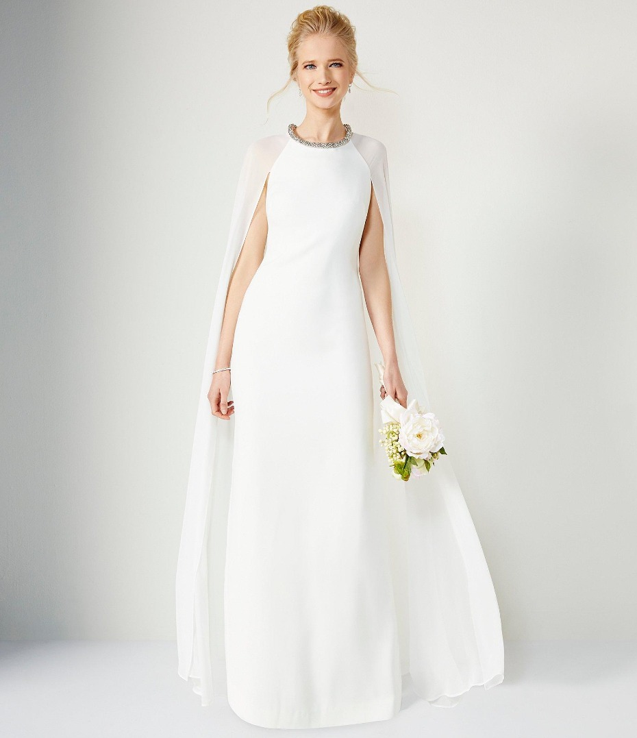 Elegant bride in white gown with cape holding bouquet