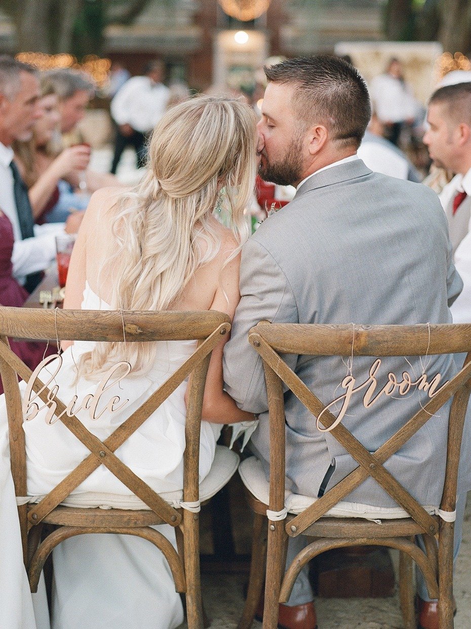 bride and groom seat signs and wedding kiss
