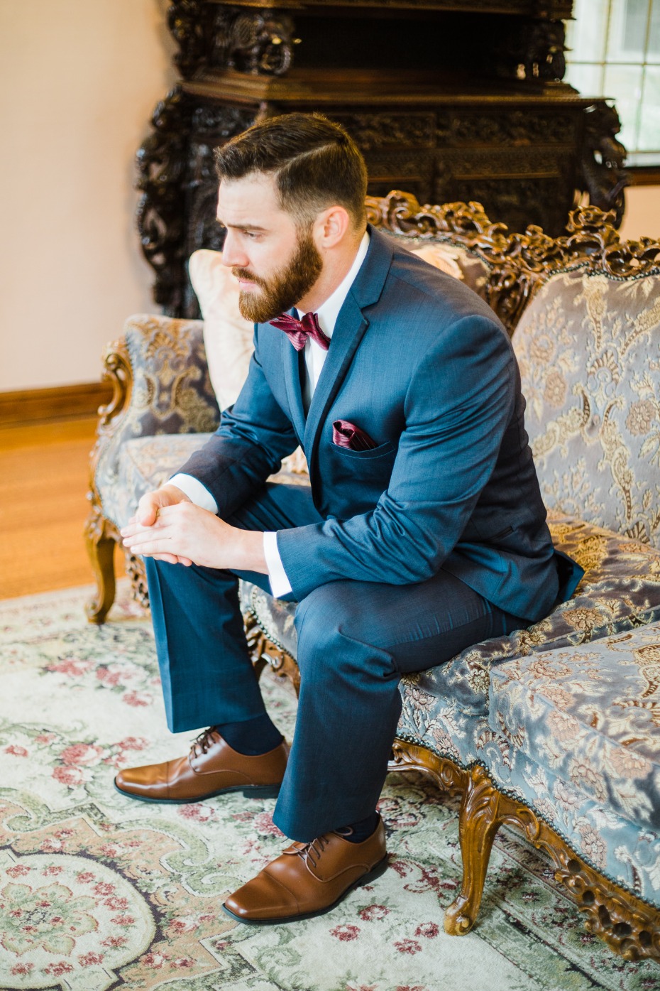 groom in blue suite and burgundy accessories