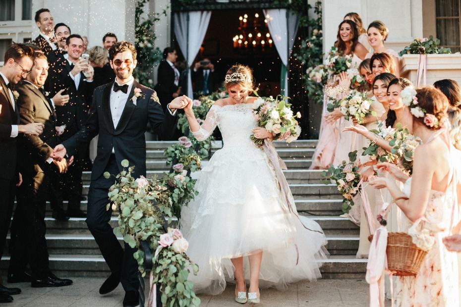 Newlyweds joyfully exiting wedding ceremony showered in confetti