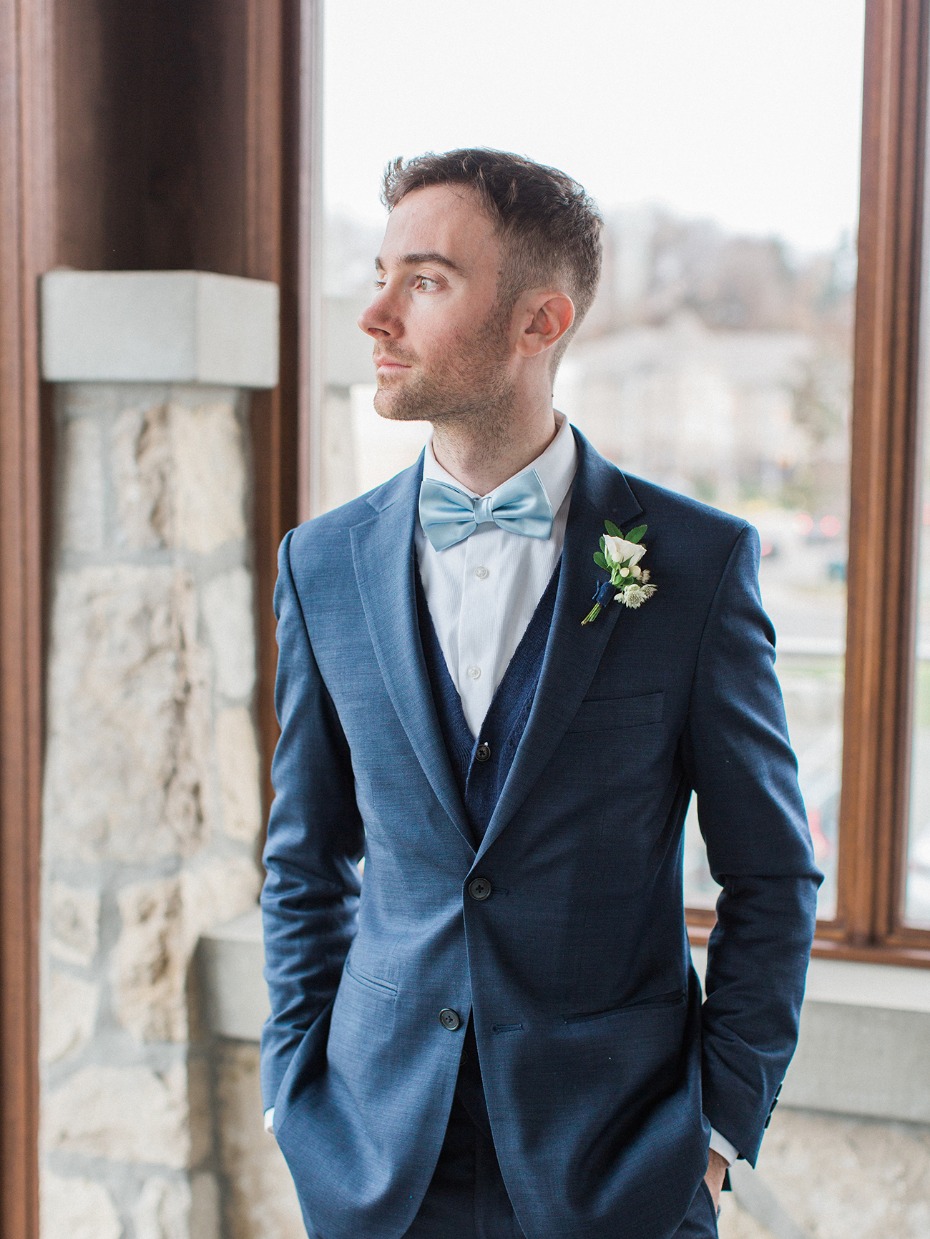 groom in navy blue suite and soft blue bow tie