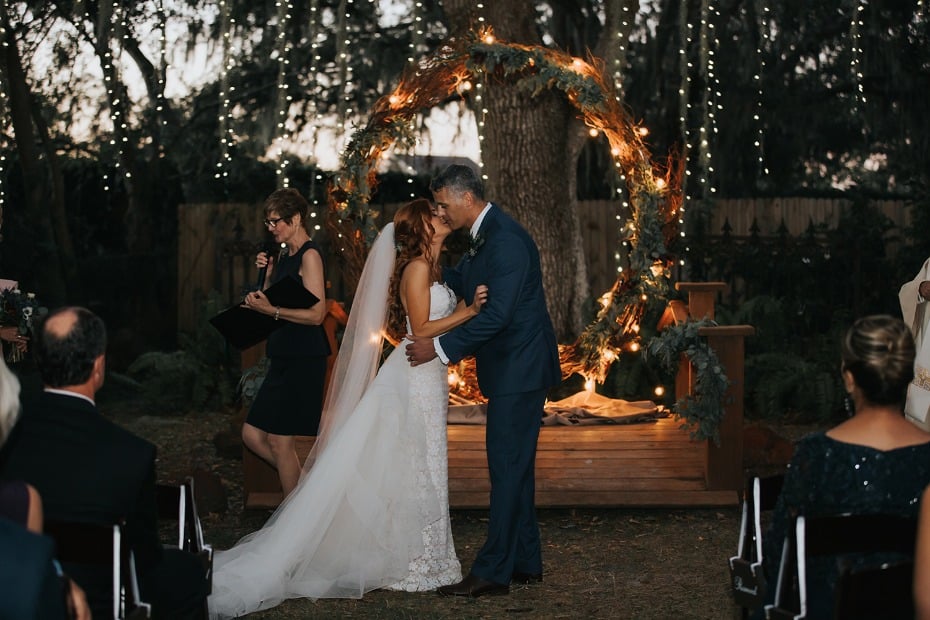 wedding kiss in front of a glowing giant wreath