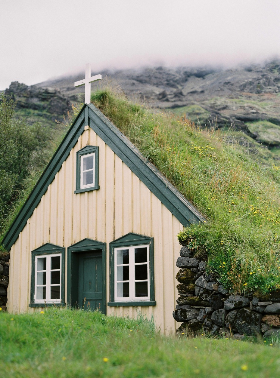 Icelandic church with grass roof and mountain backdrop