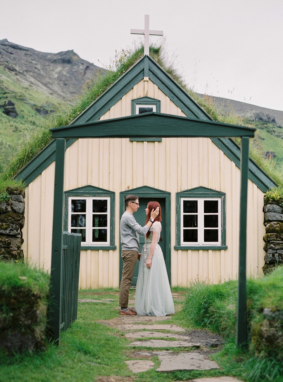 Couple in love in front of a charming green roof church building