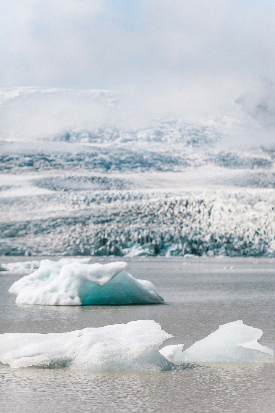 Floating icebergs in a glacial lake with mountains in the background