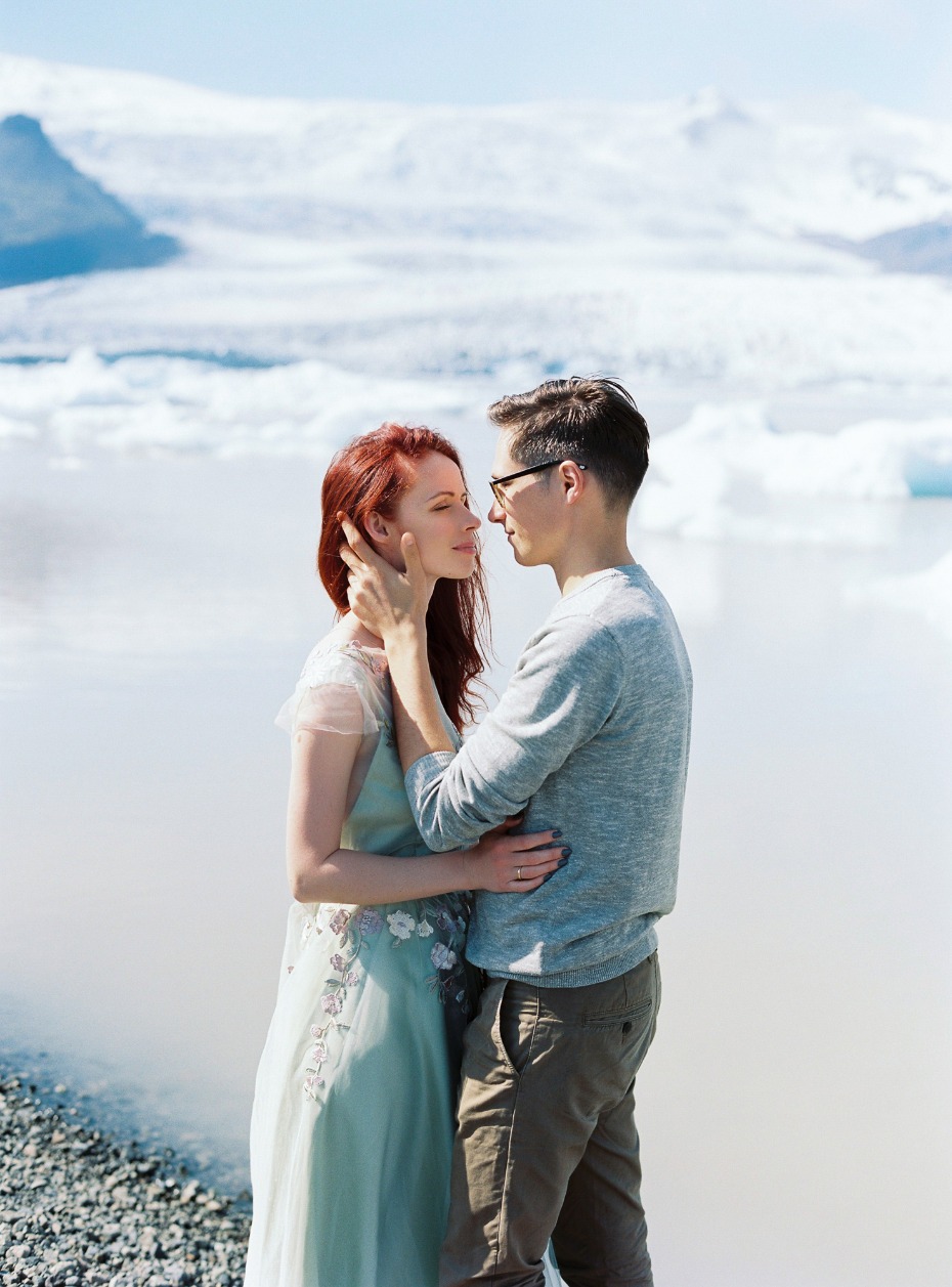 Couple embracing by a lake with a stunning icy backdrop, outdoors