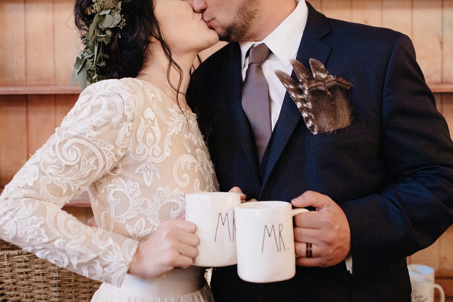 Newlywed couple share a kiss while holding Mr  mugs, a sweet moment