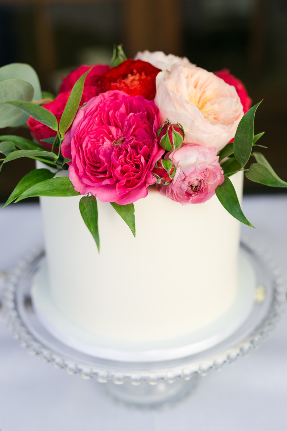 small wedding cake with hot pink and blush floral topper
